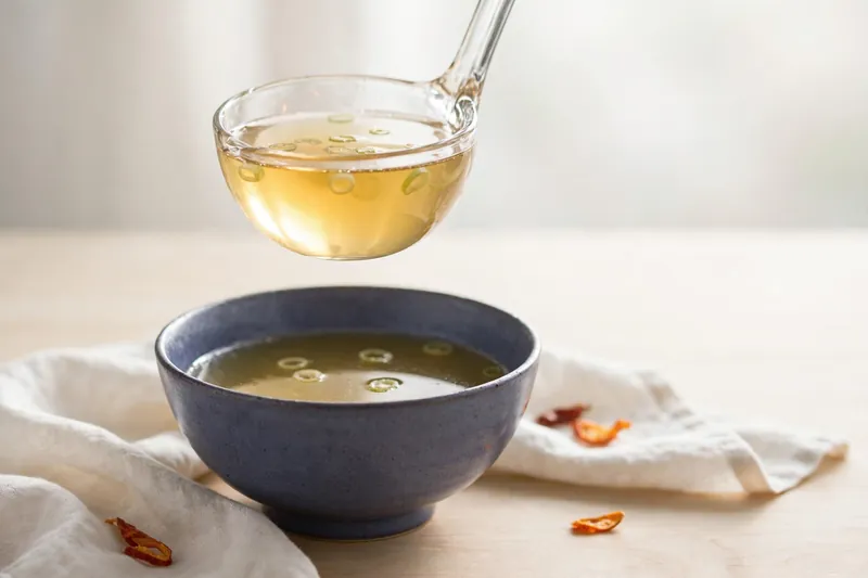 Illustration of chicken broth being ladled into a bowl