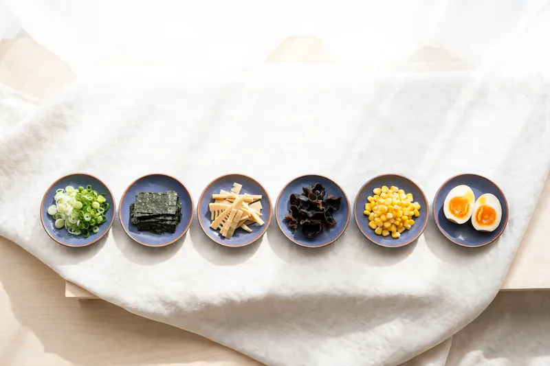 Illustration of ramen toppings set out in small dishes